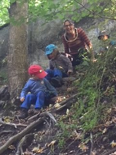 Eine Betreuerin sitzt mit einem Kind an einem Felsen