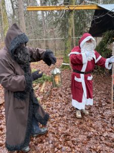 Zwei verkleidete Erwachsene als Samichlaus und Schmutzli mit Laterne im Wald