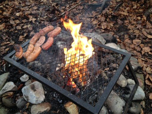 Würste auf dem Grillrost über offenem Feuer