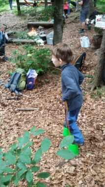 Ein Kind steht am Waldrand, im Hintergrund der Lagerplatz