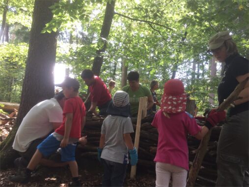 Kinder und Erwachsene schichten Äste am Bauprojekt