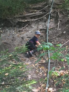Ein Kind sitzt an einem steilen Hang mit Wurzeln