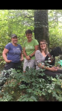 Drei Betreuerinnen stehen zusammen im Wald