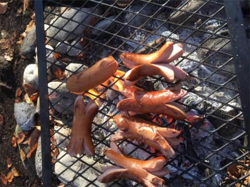 Würste liegen auf dem Grillrost über der Glut