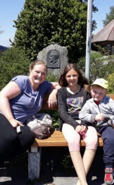 Eine Erwachsene und zwei Kinder machen Pause auf einer Bank
