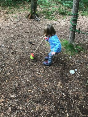Ein Kind zieht ein Spielzeug an einer Schnur über den Waldboden