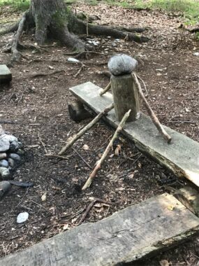 Eine Wippe aus Holzbrett und Baumstrunk auf dem Waldboden