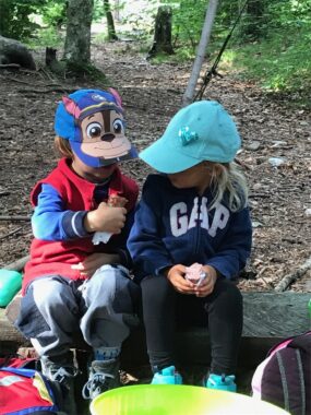 Zwei Kinder sitzen mit dem Znüni auf einer Holzbank