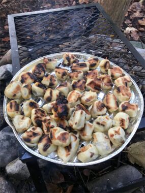 Gebackene Brötchen liegen auf einem Blech über dem Feuer