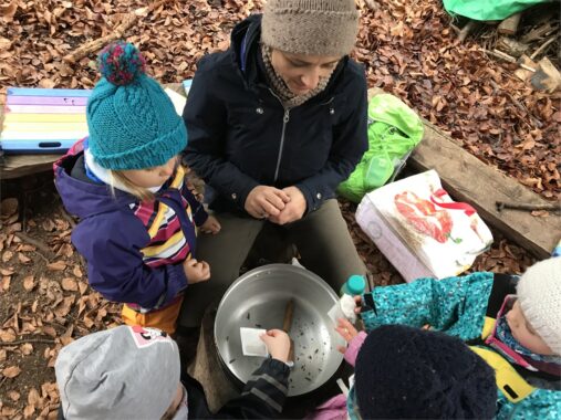 Eine Betreuerin bastelt mit Kindern an einem Holztisch