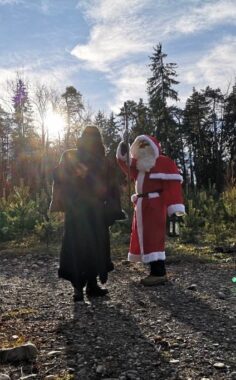 Zwei verkleidete Erwachsene gehen im Gegenlicht über den Waldweg