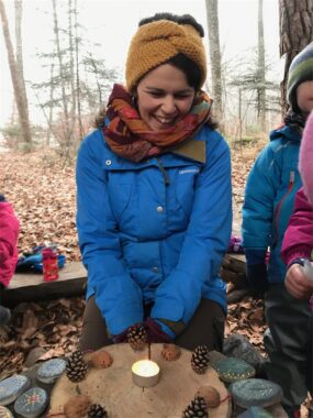 Eine Betreuerin sitzt lachend an einem Adventskranz aus Naturmaterial