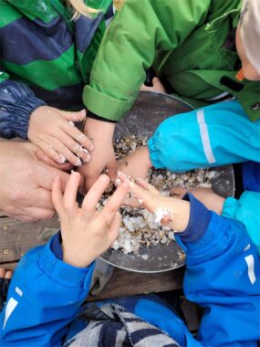 Kinderhände formen Teig in einer Metallschüssel