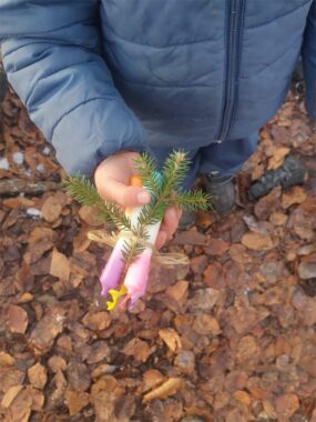 Ein Kind hält eine selbst gegossene Kerze mit Tannenzweig in der Hand