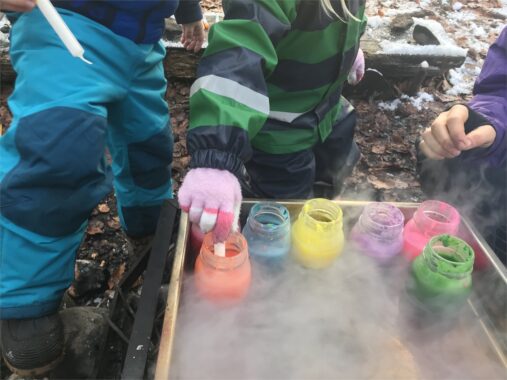 Kinder giessen farbiges Kerzenwachs in kleine Becher