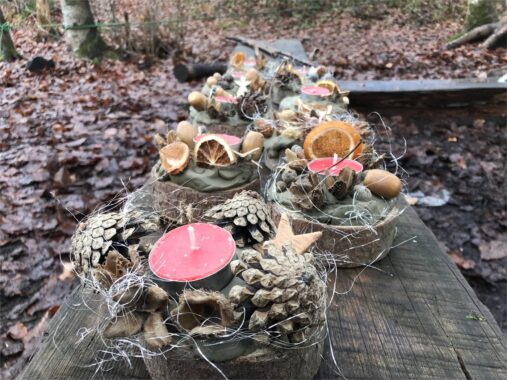 Adventsgestecke aus Tannzapfen, Moos und Kerzen auf einem Holztisch