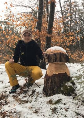 Ein Kind kniet im ersten Schnee neben der geschnitzten Pilzskulptur
