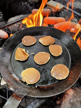 Kleine Pfannkuchen braten in der Pfanne über offenem Feuer