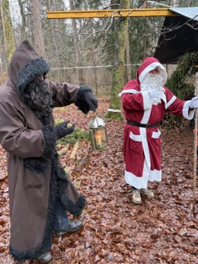 Zwei verkleidete Erwachsene als Samichlaus und Schmutzli mit Laterne im Wald